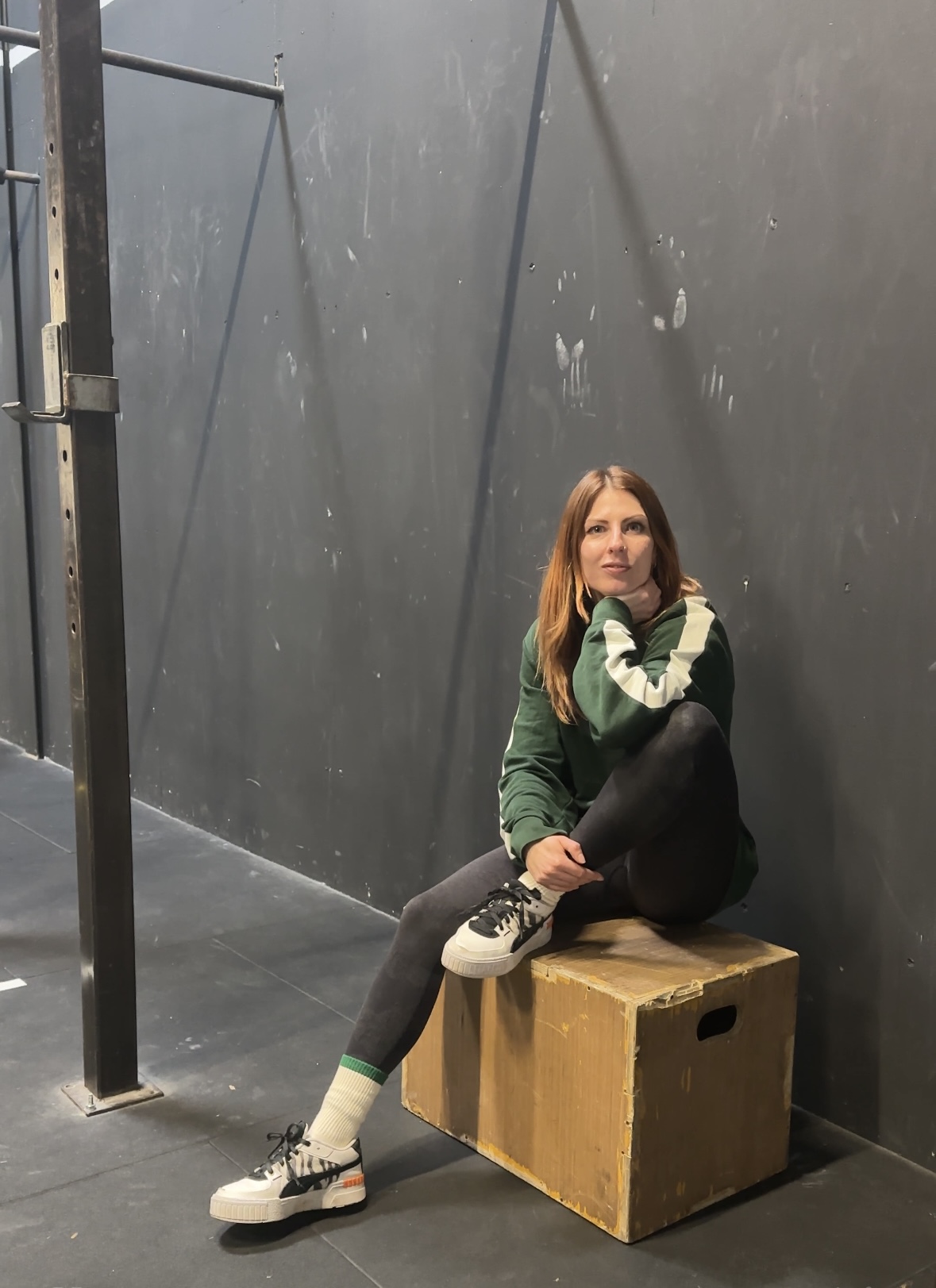 Élise, coach sportive, assise sur une box dans sa salle d'entraînement
